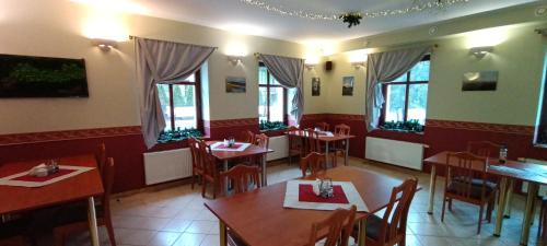 a restaurant with wooden tables and chairs and windows at Willa Akme in Stronie Śląskie