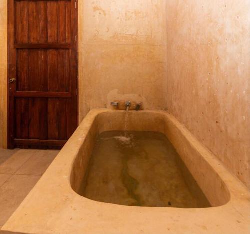 a large bath tub in a room with a door at Spectacular Hacienda Henequenera with Cenote 