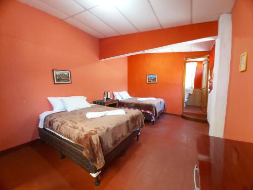 2 camas en una habitación con paredes de color naranja en Casa de Alondras, en Panajachel