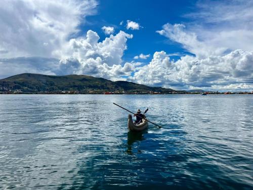 a person in a canoe on a large body of water at Uros TITIKAKA the Best lodge in Puno