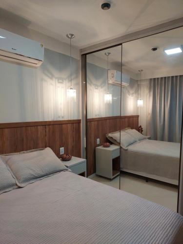ein Schlafzimmer mit zwei Betten und einem Spiegel in der Unterkunft Guarajuba, Camaçari, Bahia, 2 quartos com suíte, cobertura, terraço in Camassari