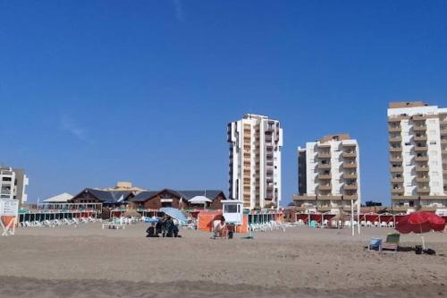una playa con algunos edificios y algunas sillas y sombrillas en Monoambiente en Villa Gesell