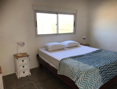 1 dormitorio con 1 cama grande y ventana en Casa de Coral en Punta Del Diablo