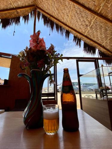 Una botella de cerveza y un jarrón con flores en una mesa. en VIAJEROS TUQUILLO BEACH, en Huarmey