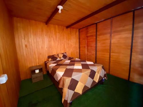 1 dormitorio con 1 cama en una habitación con paredes de madera en VIAJEROS TUQUILLO BEACH, en Huarmey