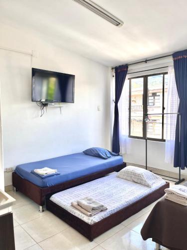 a bedroom with two beds and a flat screen tv at Apartaestudio Centro Pereira un solo ambiente in Pereira