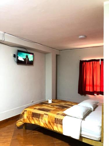 1 dormitorio con 1 cama y TV en la pared en Hotel Los Chankas, en Ayacucho