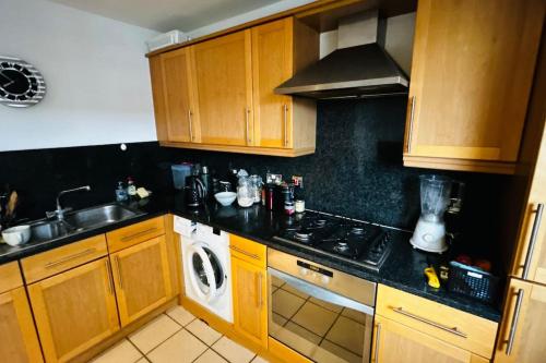 a kitchen with wooden cabinets and a stove top oven at Baker Street 2 Bed Apartment in London