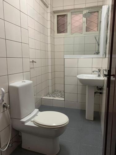 a white bathroom with a toilet and a sink at Chambre Centre de Maputo in Maputo