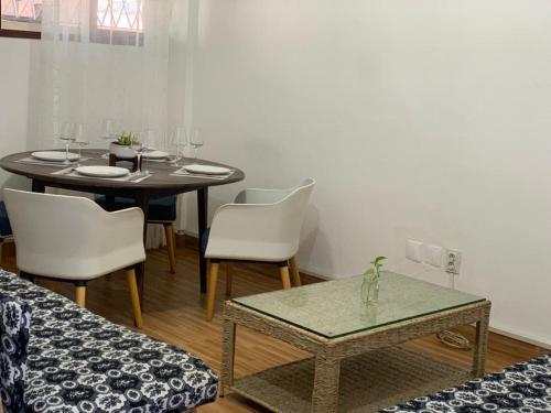 a dining room with a table and white chairs at Chambre Centre de Maputo in Maputo