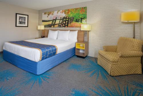 マナッサスにあるDays Inn by Wyndham Manassas Battlefieldのベッドと椅子付きのホテルルーム