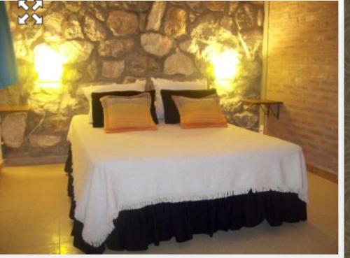 Villa Pio في هويرتا غراندي: سرير في غرفة بجدار حجري