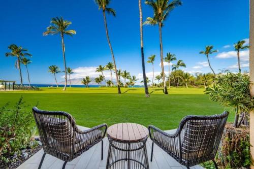 a patio with two chairs and a table and a lawn at KIHEI SURFSIDE #110 condo in Wailea