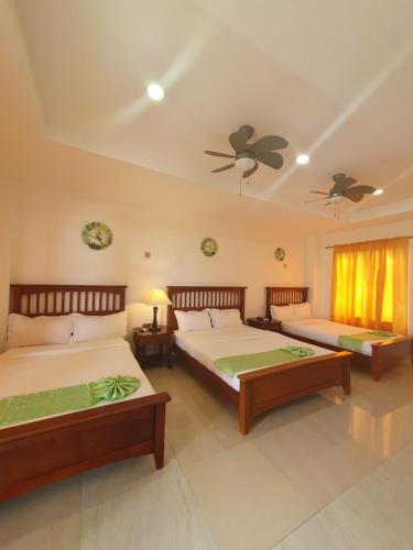 a bedroom with two beds and a ceiling fan at Moalboal Tropics in Moalboal