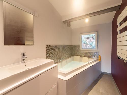 ein weißes Badezimmer mit einer Badewanne und einem Waschbecken in der Unterkunft Magnificent accommodation for 7 travellers with hot tubs in Esneux