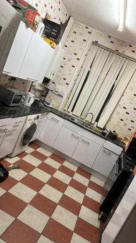 a kitchen with white cabinets and a checkered floor at 28 Vicarage Street in Failsworth