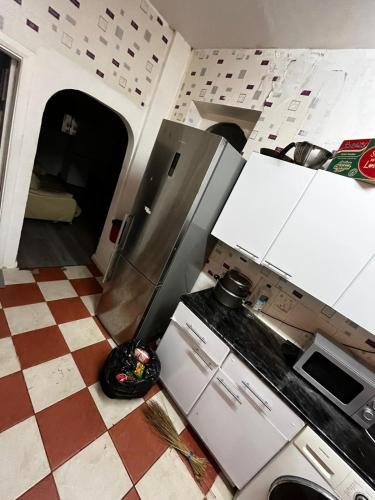 a kitchen with white cabinets and a checkered floor at 28 Vicarage Street in Failsworth