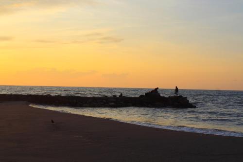 a group of people sitting on a rock in the ocean at Hotel Partenon Beach in La Ceiba