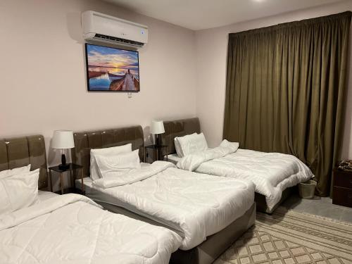 um quarto de hotel com duas camas e uma televisão em منتجع شاطيء جوفالي GUVALI Beach شاليه طراز ميكانوس Siyal سيال سابقاً em Jeddah