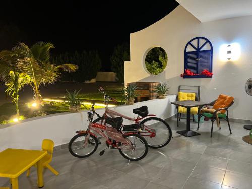 Duas bicicletas estacionadas num pátio com uma mesa e cadeiras em منتجع شاطيء جوفالي GUVALI Beach شاليه طراز ميكانوس Siyal سيال سابقاً em Jeddah