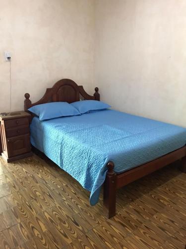 a bedroom with a bed with a blue bedspread and a nightstand at La casona de San José in Cachí