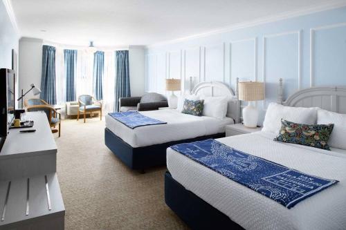 um quarto de hotel com duas camas e um sofá em Coventry Motor Inn em São Francisco