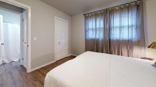 a white bedroom with a large bed and a window at Hazel's Hideaway apt in walkable historic area in Snohomish