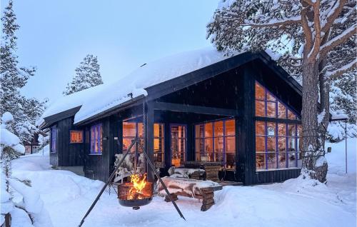 a log cabin in the snow with a fire at Stunning Home In Rjukan With Wifi in Rjukan