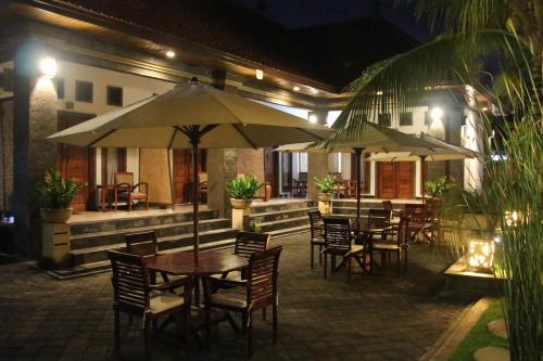 an outdoor patio with tables and chairs and umbrellas at night at Kubu Garden Suites & Villas Nusa Dua in Nusa Dua
