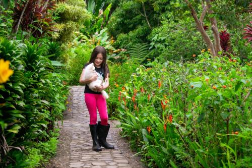 a girl standing in a garden holding a stuffed animal at Hotel Claro de Luna in Monteverde Costa Rica