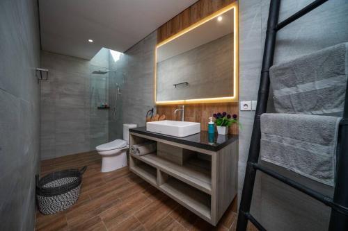 La salle de bains est pourvue d'un lavabo, de toilettes et d'un miroir. dans l'établissement Astaga Villa 1 Canggu, à Canggu