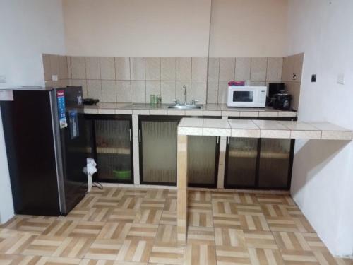eine Küche mit einer Theke, einer Mikrowelle und einem Kühlschrank in der Unterkunft Apartamentos HJJ in Puerto Limón