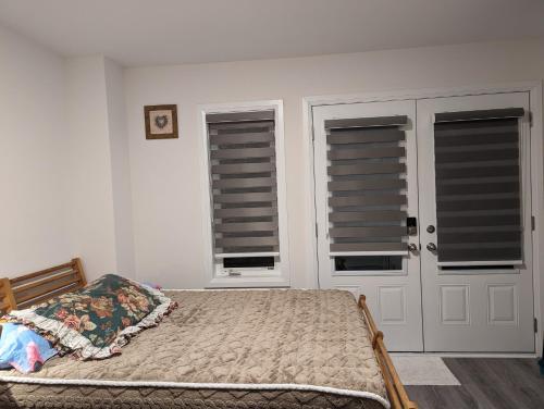 a bedroom with a bed and two windows with shutters at Bright Room full of love and warmth in Bowmanville