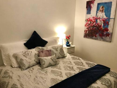 een slaapkamer met een bed met kussens en een schilderij bij BEACH Living - “A bit of Mykonos near Mordialloc!” in Aspendale