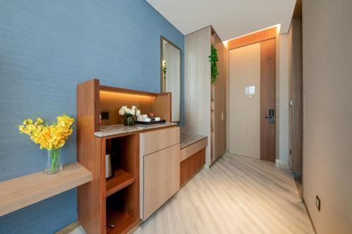 a bathroom with a blue wall and a vase of flowers at Shan Zhi Ye Serviced Apartment Hotel - Houjie Wanda Plaza Liaoxia Subway Station in Dongguan