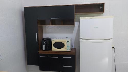 a small kitchen with a microwave and a refrigerator at CASA DISPONÍVEL PARA TEMPORADA in Bertioga