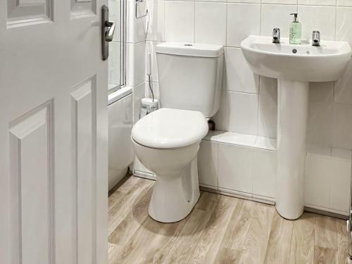 a white bathroom with a toilet and a sink at Derwent Cottage in Keswick