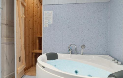 a bath tub in a bathroom with a blue wall at 3 Bedroom Stunning Apartment In Dannemare in Dannemare