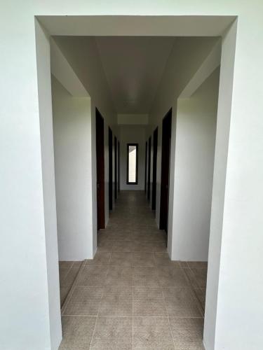 an empty hallway with white walls and a tile floor at Haven Suites Siargao in General Luna