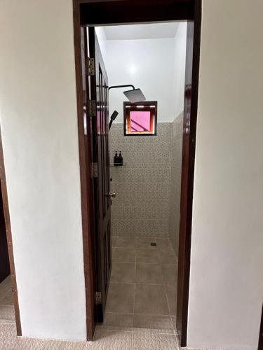 a hallway with a bathroom with a shower and a door at Haven Suites Siargao in General Luna