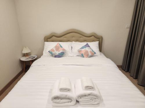 a bed with white sheets and two towels on it at Vicky the east ville Bangsean room 15 in Ban Hua Khao Sammuk