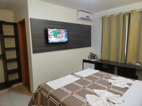 a bedroom with a bed and a tv on the wall at Di Napoli Plaza Hotel in Gurupi