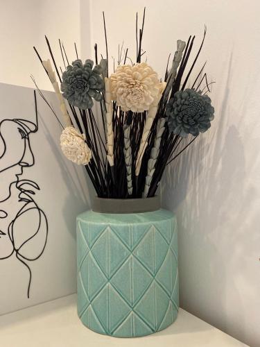 a blue vase with flowers in it next to a wall at HM - HouseMirage in Paço de Arcos