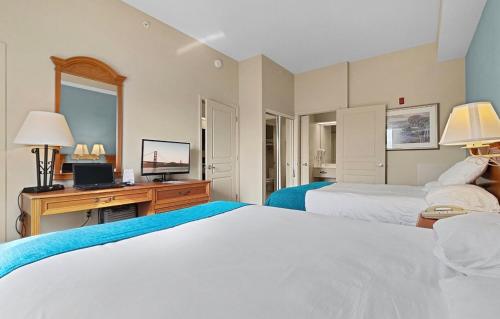 a bedroom with two beds and a desk with a television at Resort Hotel Condo near Disney parks - Free parks shuttle in Orlando