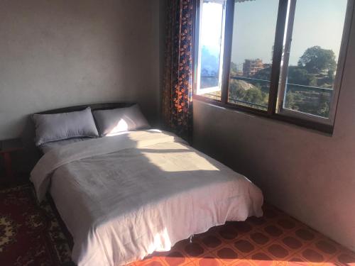 a bedroom with a bed with a large window at Sunrise Point Homestay in Nagarkot