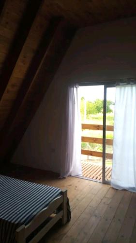 um quarto no sótão com uma cama e uma janela em La Alpina em Saladillo