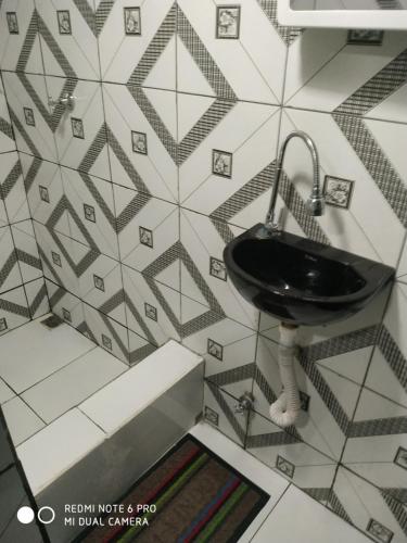 a bathroom with a black sink on a tiled wall at RESIDENCIAL ESPERANÇA in Teresina
