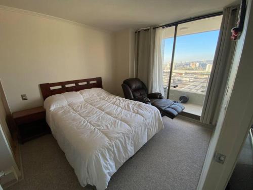 a bedroom with a bed and a chair and a window at Hermoso Departamento con excelente vista, a pasos de la Quinta Vergara, cercano a Reloj de Flores y Playa Caleta Abarca in Viña del Mar