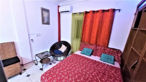 a bedroom with a bed with red sheets and blue pillows at The Yafé Bastos 4 in Yaoundé