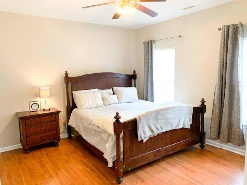 Un dormitorio con una cama de madera con ventilador de techo. en *Come home - 1 mile from Duke & Downtown Durham, en Durham